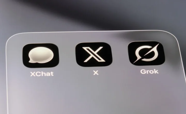 Close-up of a screen with three black app icons labeled XChat, X and Grok inside a rounded rectangular panel.