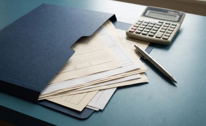 A navy folder holds blank cream forms beside a calculator and a silver pen on a blue surface, shown in a close-up AI-generated illustration.