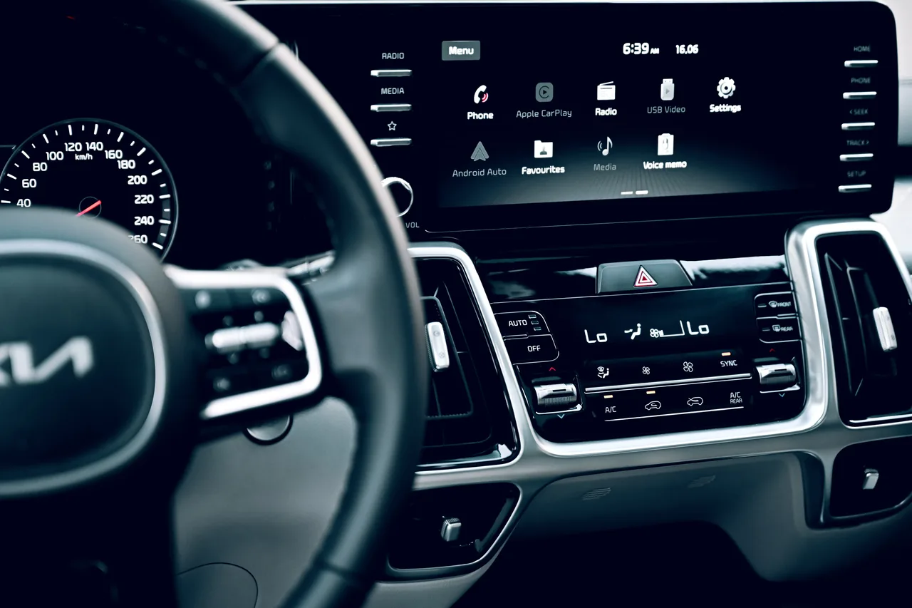 A Kia dashboard touchscreen showing phone, Apple CarPlay, radio and settings icons.